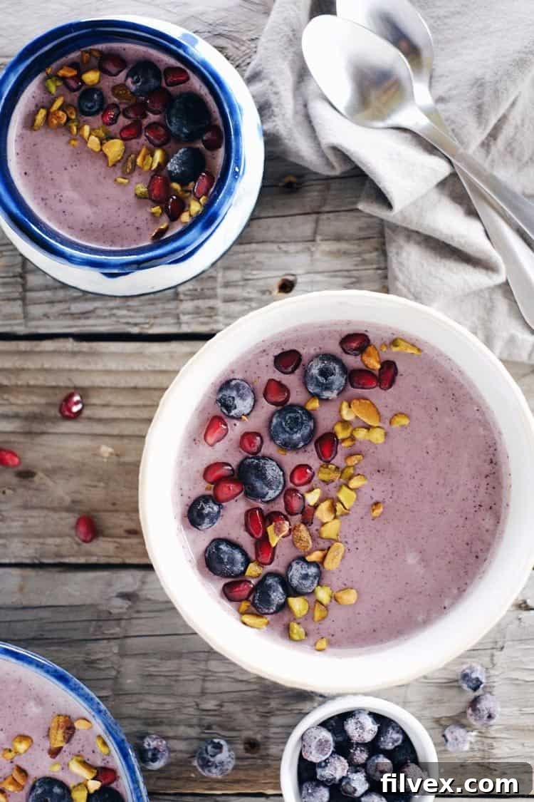 Overhead image of a beautifully garnished Berry Protein Smoothie Bowl, featuring fresh blueberries, pomegranate seeds, and chopped nuts.