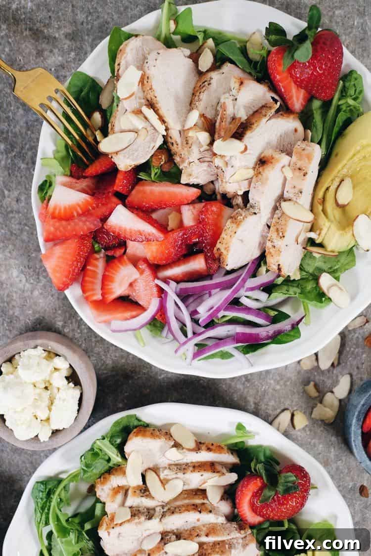 Close-up of golden-brown baked chicken breast, seasoned simply with salt and pepper, sliced into strips, ready to be tossed into a fresh strawberry salad.
