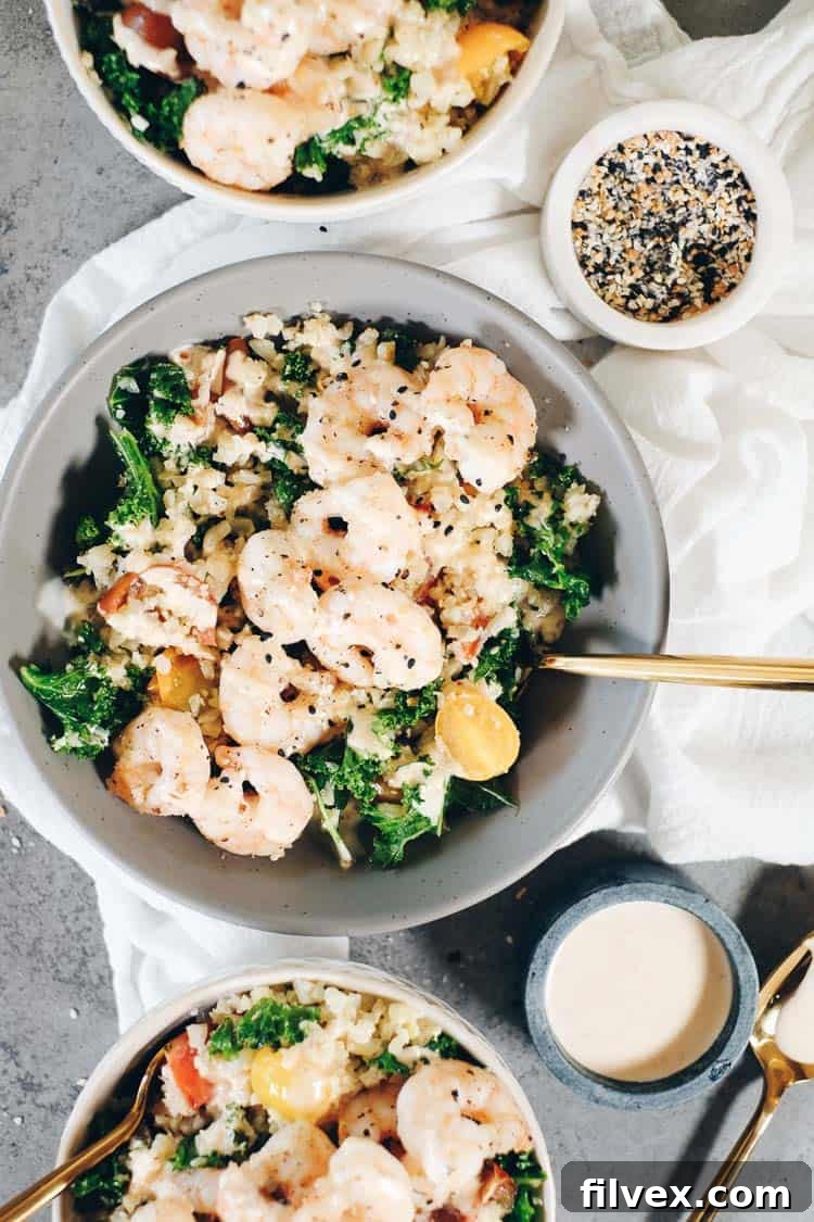 A vibrant close-up of Paleo cauliflower rice with shrimp and fresh vegetables in a bowl.