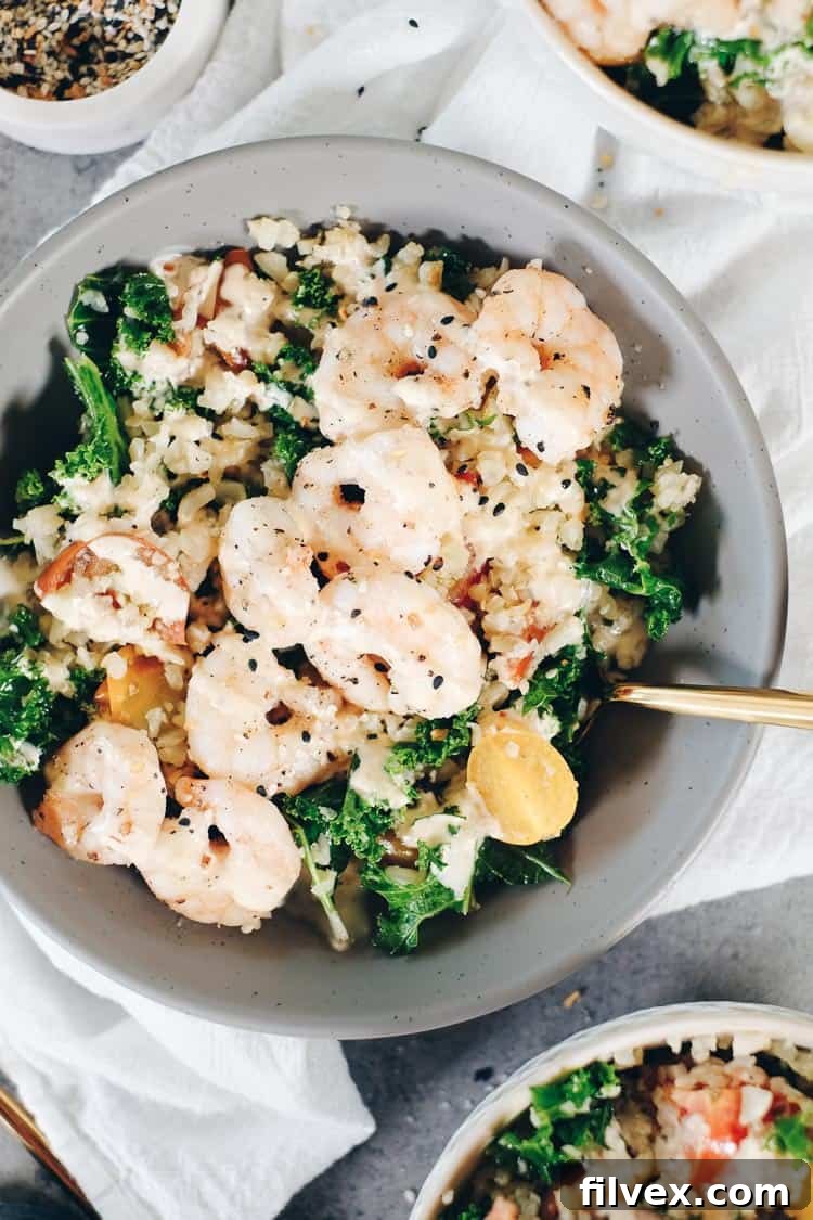 Drizzling creamy, dairy-free sauce over a freshly prepared Paleo cauliflower rice and shrimp bowl.