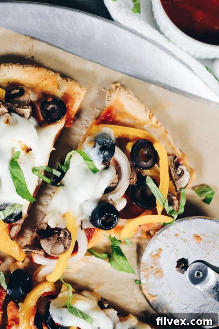 A slice of customizable Paleo pizza with various toppings, showcasing the versatility of the recipe. Grain-free and dairy-optional, perfect for any preference.