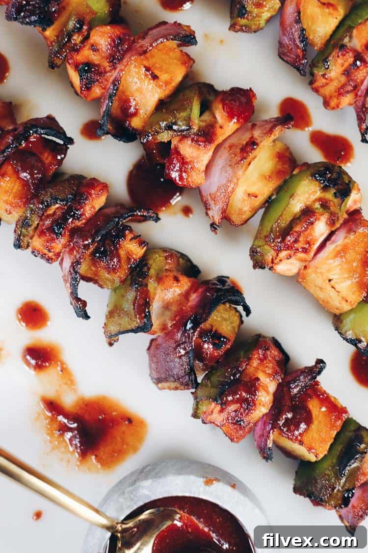 Close-up of raw Hawaiian chicken kabobs with colorful vegetables and pineapple threaded on skewers, ready for grilling.