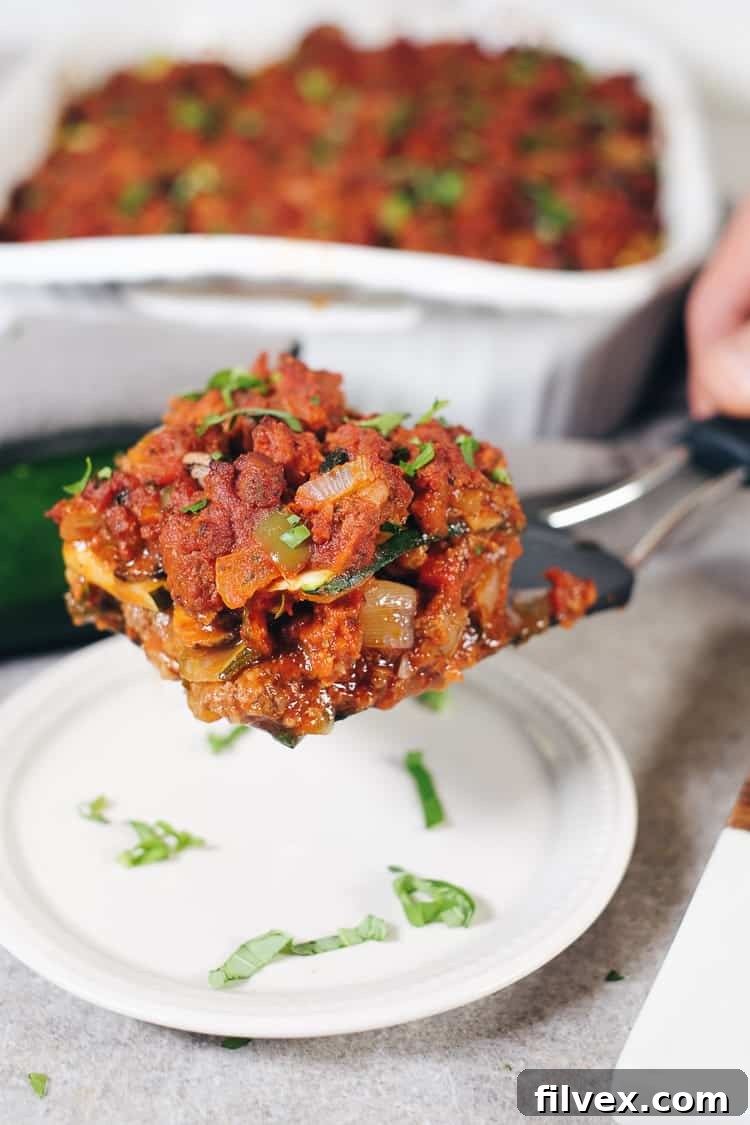 A neatly arranged stack of thinly sliced zucchini strips on a cutting board, ready for a grain-free lasagna. These precisely cut vegetable noodles are fundamental for achieving the desired texture in healthy, low-carb recipes.