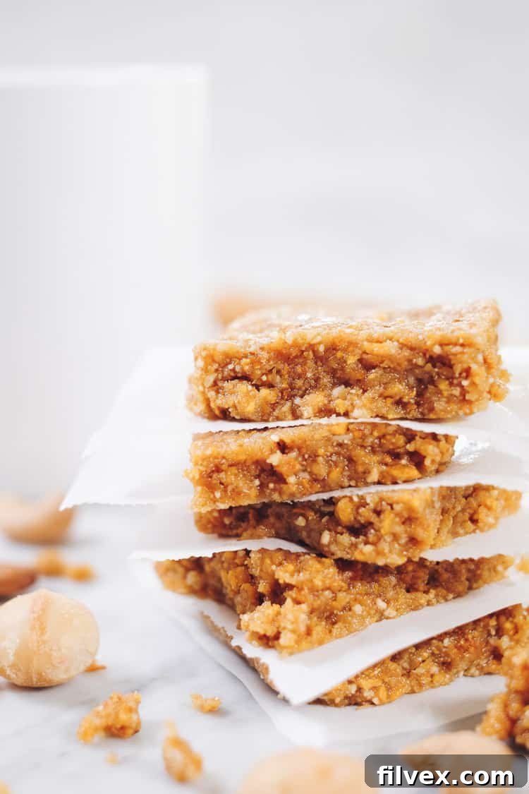 A selection of no-bake mango bars, some cut into squares and others into rectangular bars, displayed on a clean white surface with a minimalist aesthetic. Highlighted as a versatile, healthy snack option for any time of day.