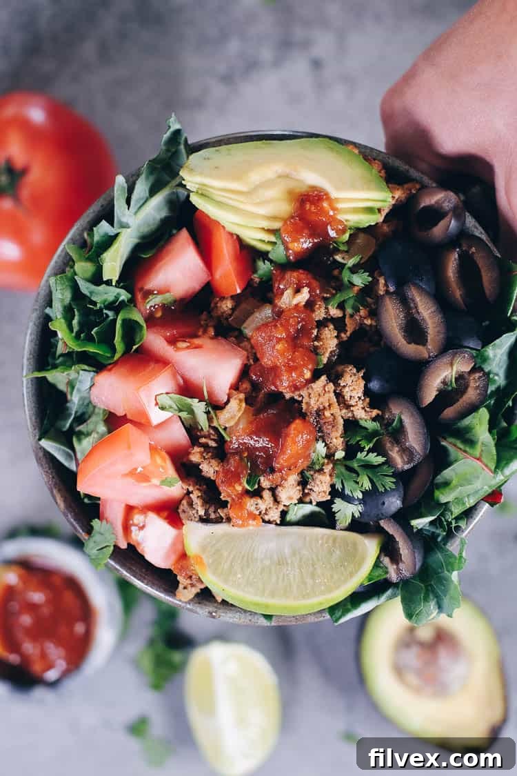 Vibrant and fresh Paleo Taco Salad in a bowl, featuring seasoned ground turkey, mixed greens, diced avocado, tomatoes, and black olives, with a squeeze of lime. Ideal for Whole30 and Keto diets.