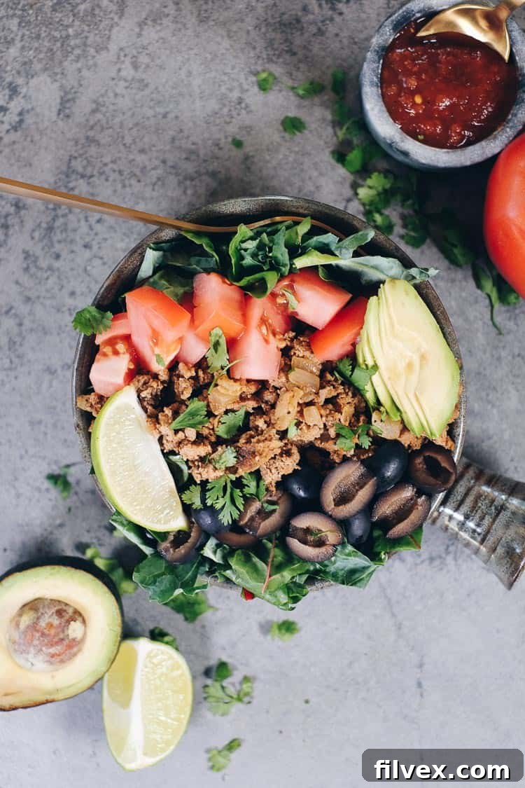 Close-up of the fresh ingredients for a Paleo Taco Salad: vibrant mixed greens, diced tomatoes, sliced olives, and creamy avocado, ready to be combined with seasoned ground turkey.