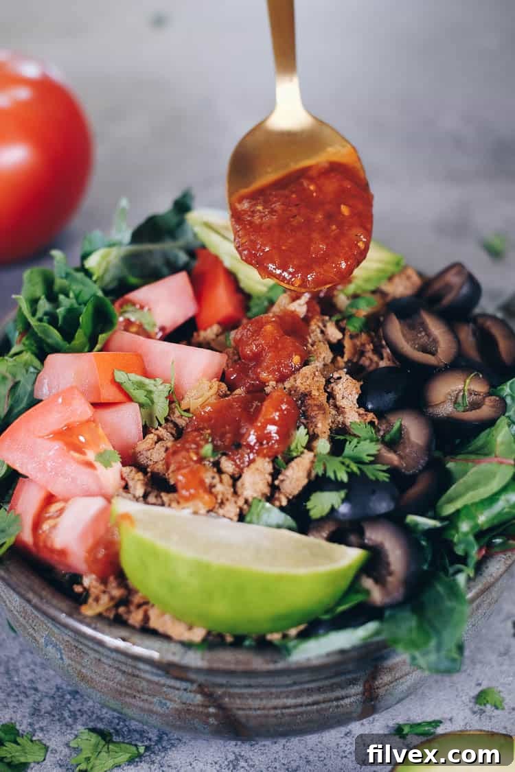 A close-up of a generous serving of Paleo Taco Salad, featuring a colorful mix of ground turkey, fresh greens, avocado, tomatoes, olives, and cilantro, ready to be enjoyed.