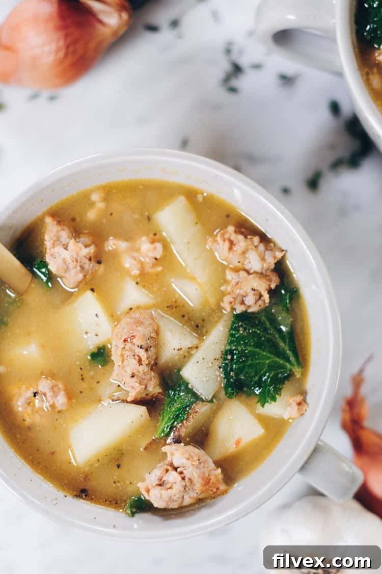 A close-up shot of a steaming bowl of Paleo sausage soup, garnished with fresh herbs, showcasing its rich texture.