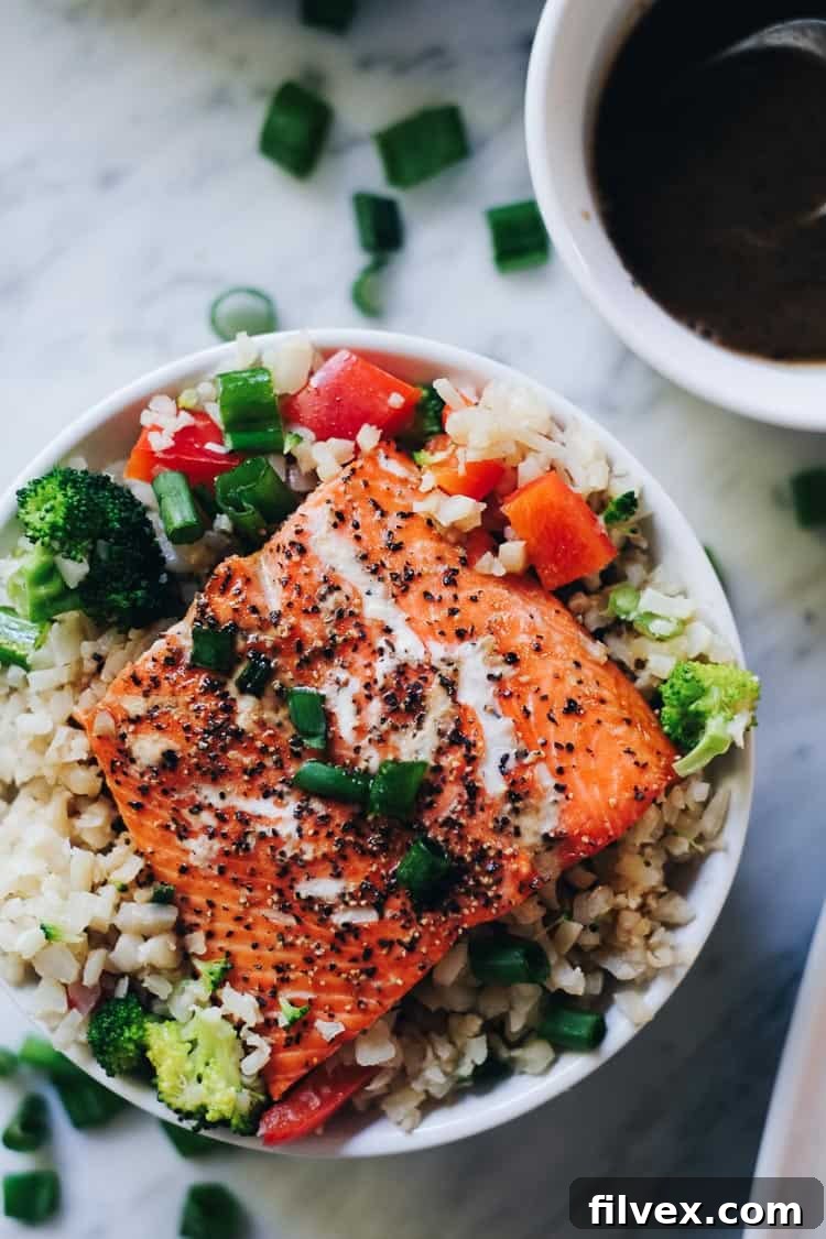 A delicious and healthy Honey Ginger Salmon Bowl with baked salmon, cauliflower rice, broccoli, bell peppers, and a homemade honey ginger sauce. Perfect for a quick and easy weeknight dinner, Paleo, Gluten-Free and Soy-Free. | realsimplegood.com