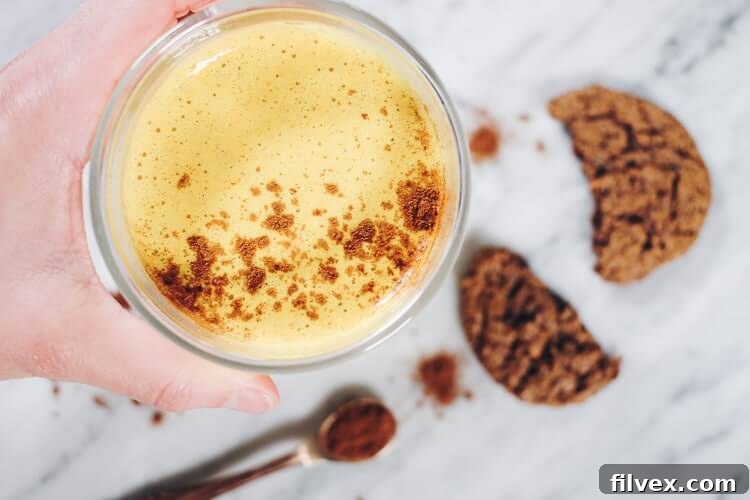 An overhead shot of three Pumpkin Turmeric Lattes in charming mugs, garnished with cinnamon, perfect for sharing during the holidays. This dairy-free, Paleo, Vegan, and Refined Sugar-Free recipe offers all the beloved fall flavors, found on realsimplegood.com.
