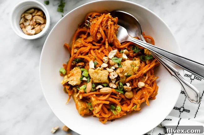 Horizontal overhead image of a bowl of homemade Sweet Potato Chicken Pad Thai with noodles gracefully swirled around a fork, ready to be enjoyed. 
