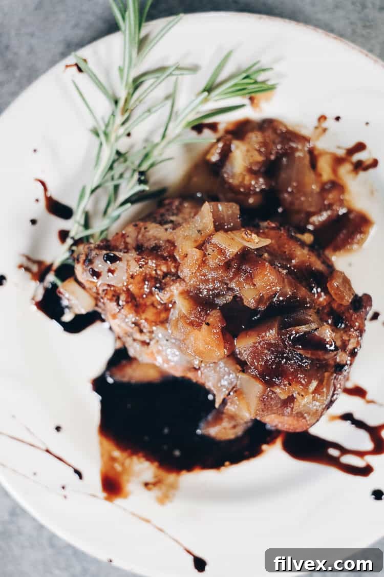 Perfectly cooked Instant Pot boneless pork chops with a vibrant apple balsamic topping, resting on a serving platter. This image showcases the golden-brown sear on the pork and the glistening sauce, highlighting its appeal for a quick, healthy, and family-friendly Paleo and Whole30 meal.