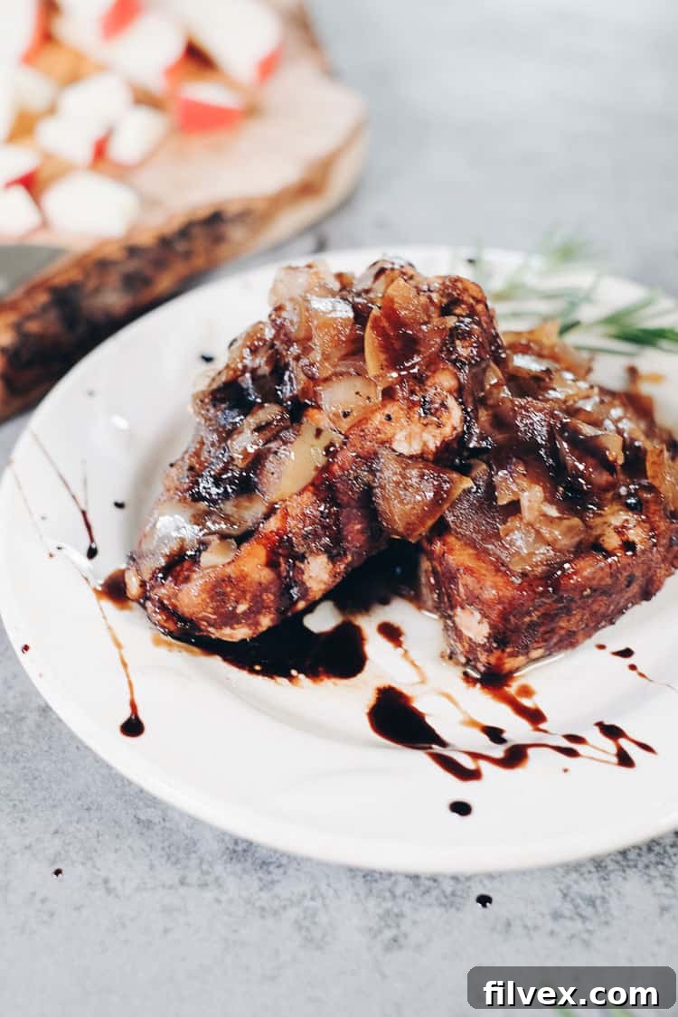 Close-up shot of juicy Instant Pot pork chops, generously coated with a sweet and tangy apple balsamic reduction, garnished with fresh herbs. The rich colors of the sauce and tender pork are prominent, emphasizing the quick and healthy nature of this Paleo and Whole30 recipe.