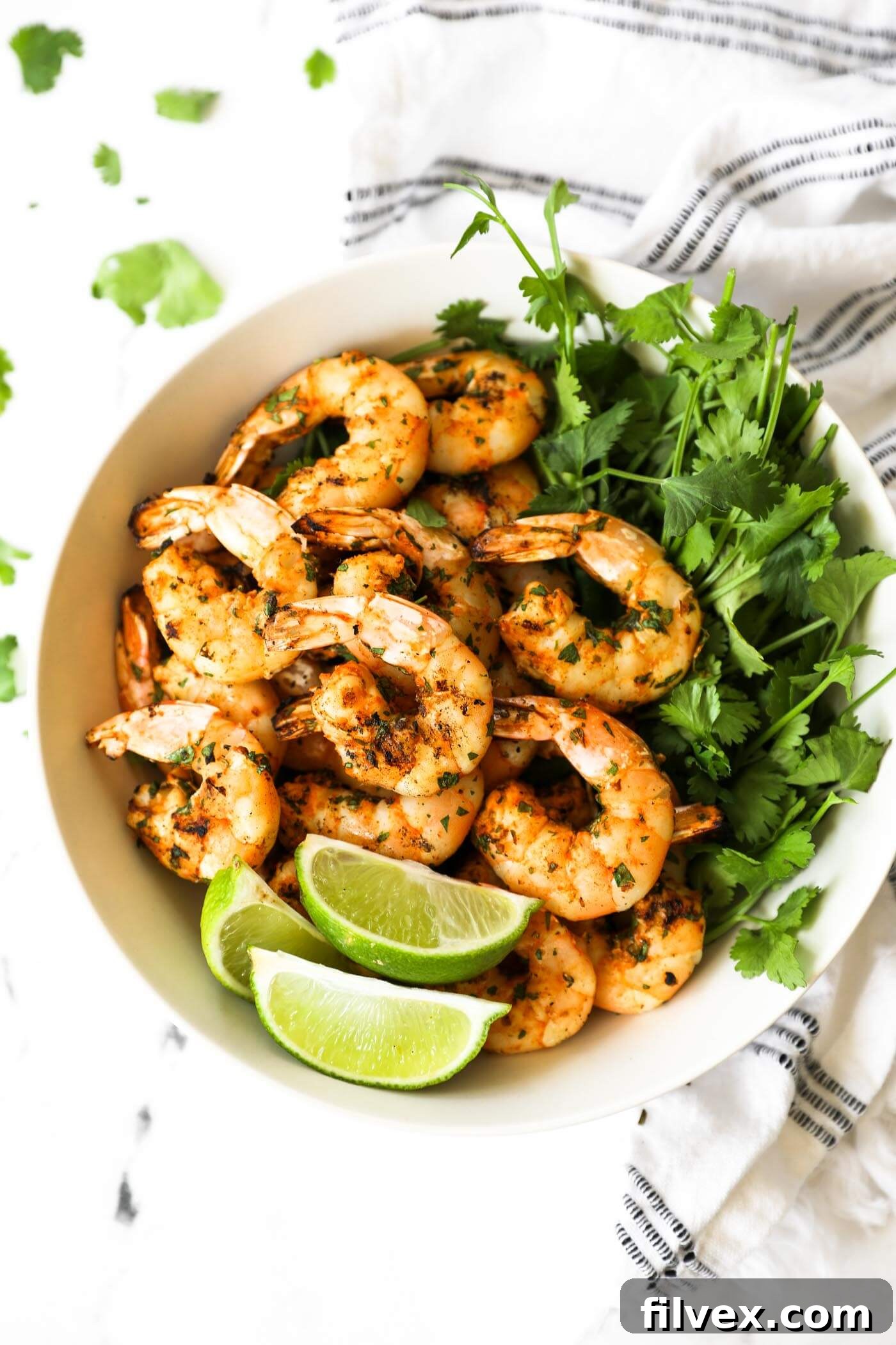 Shrimp pulled off the kabobs and piled in a bowl with fresh cilantro and lime wedges.
