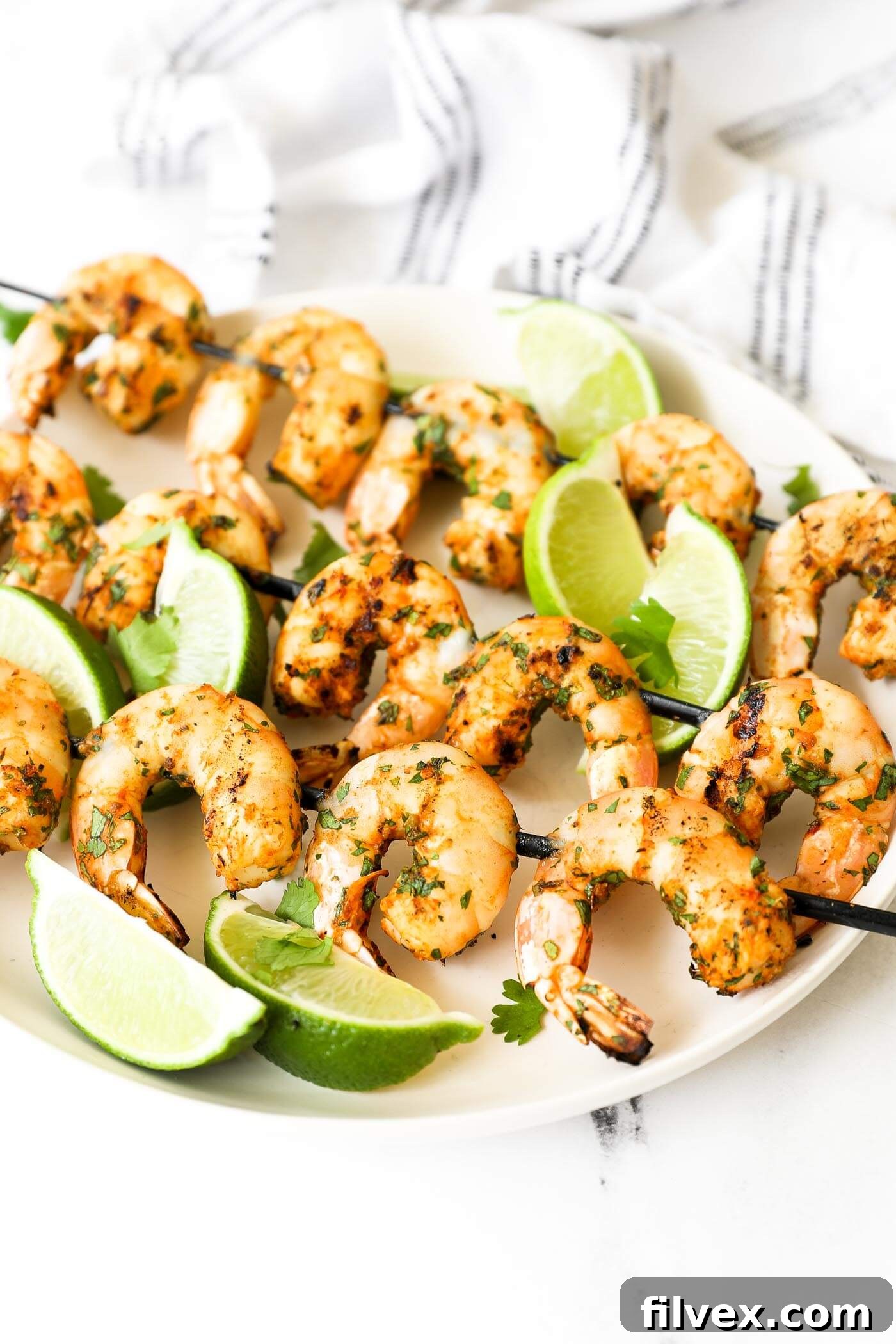 Angled image of skewers on a plate. Grilled shrimp kabobs with