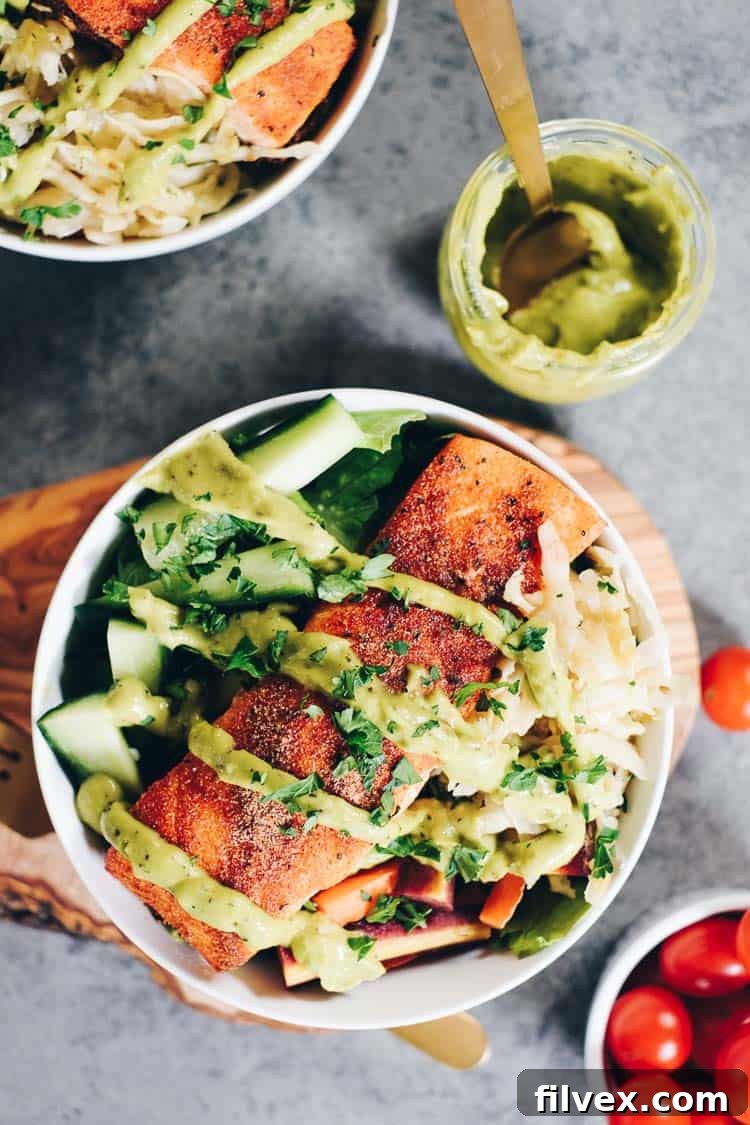 Overhead image of cooked salmon over greens in a bowl with vibrant green sauce on top
