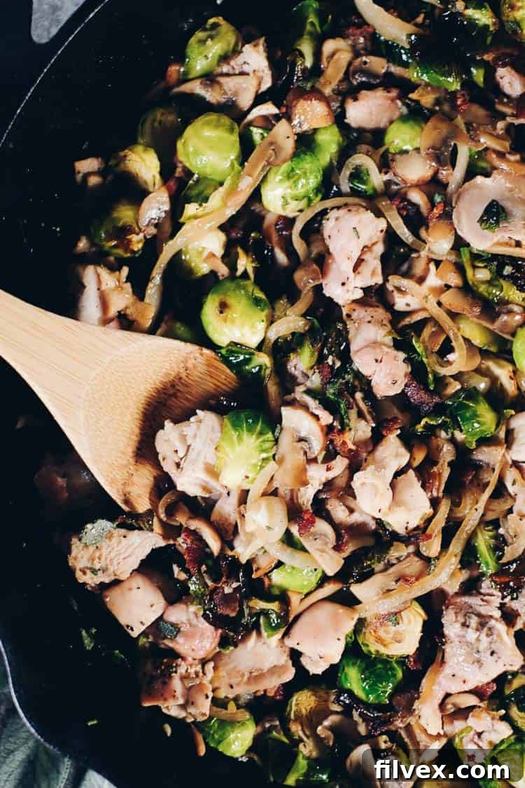 A close-up shot of the dairy-free creamy sauce coating the chicken and brussels sprouts in the skillet. Ideal for #paleolife #whole30 #recipe #dairyfree #glutenfree meals. | realsimplegood.com