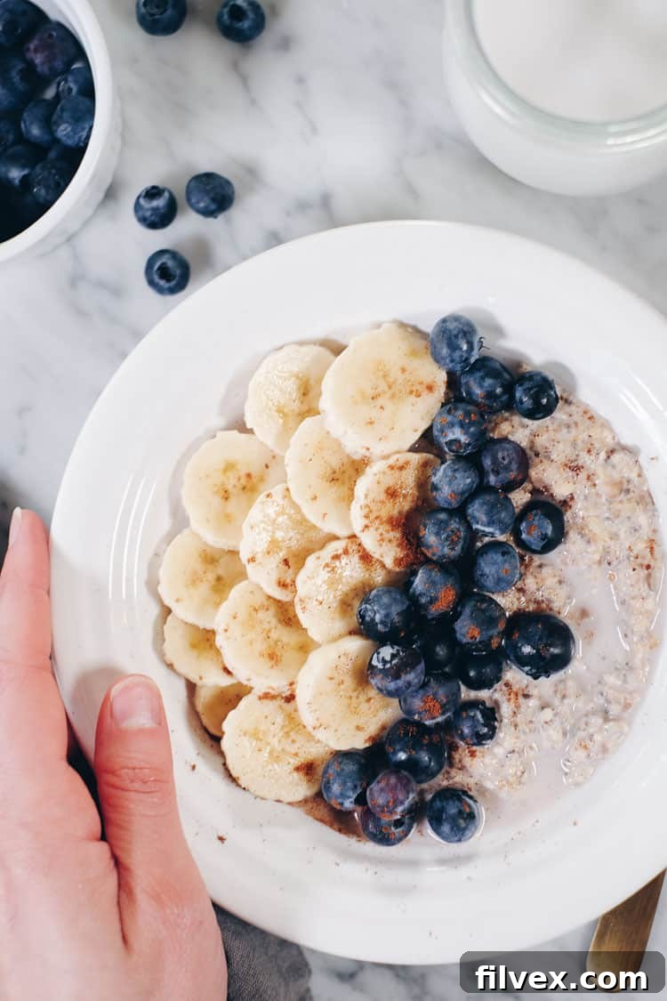 Overhead view of a glass jar filled with creamy Paleo Overnight Oats, garnished with vibrant fresh fruit and a hint of cinnamon, emphasizing the healthy and convenient nature of this Whole30 compliant breakfast.