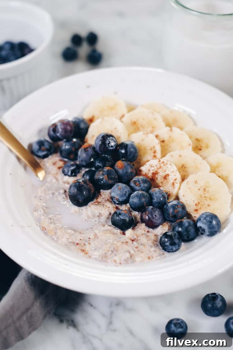 A spoon digging into a jar of Paleo Overnight Oats, showing the rich, creamy texture and a mix of colorful fruit toppings. This image conveys the deliciousness and convenience of this healthy breakfast.