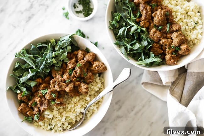 Two bowls of Easy Curry Beef Bowls, featuring vibrant greens and fluffy cauliflower rice. Garnished with fresh chopped parsley, forks are ready for digging in.