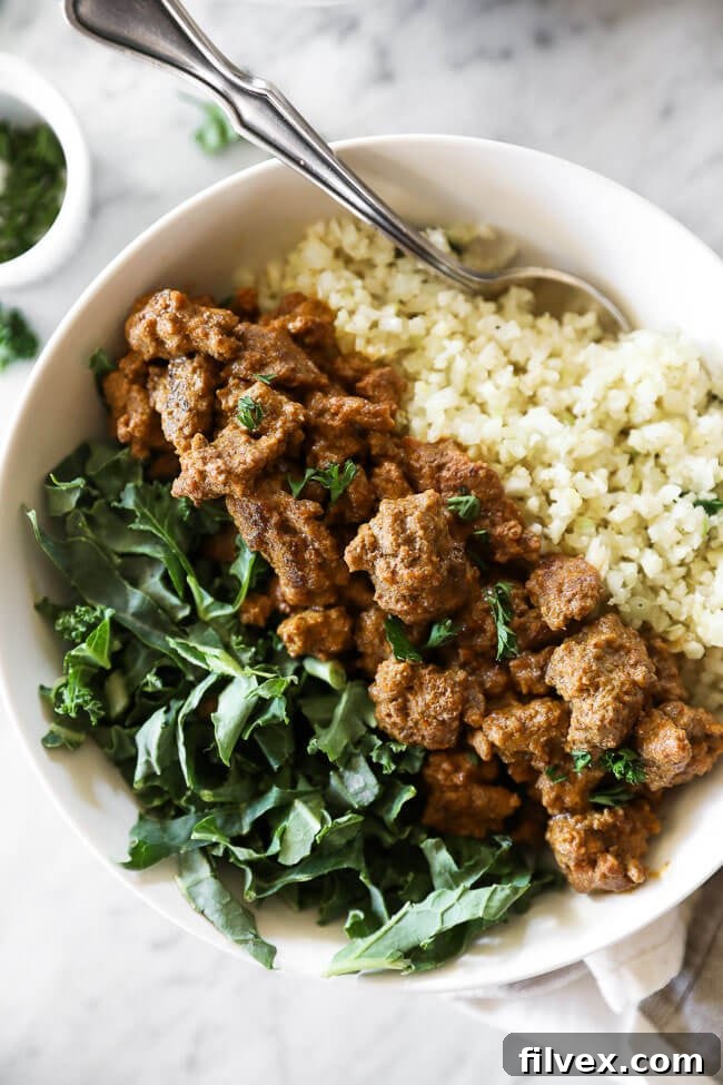 An enticing close-up of a single Easy Curry Beef Bowl, showcasing the succulent curry beef nestled on a bed of fresh greens and delicate cauliflower rice.