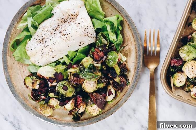 Perfectly cooked pan-seared cod fillets served alongside crispy garlicky bacon Brussels sprouts on a plate, ready to eat.