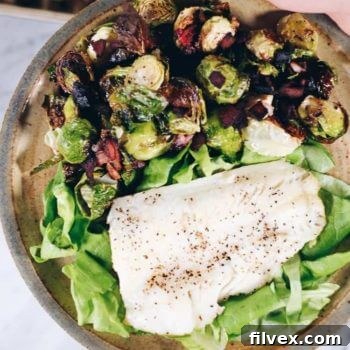 Pan-seared cod with garlicky bacon Brussels sprouts, garnished with fresh herbs, presented as a complete and appealing meal.