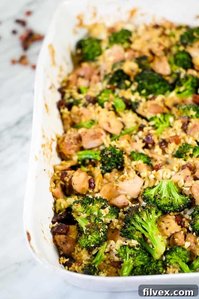 The wholesome chicken and broccoli casserole with bacon and cauliflower rice, displayed in a rustic baking dish, showcasing its appealing texture. 