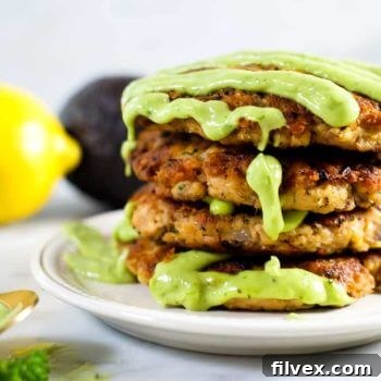 Delicious salmon patties with a vibrant green sauce drizzled over them.