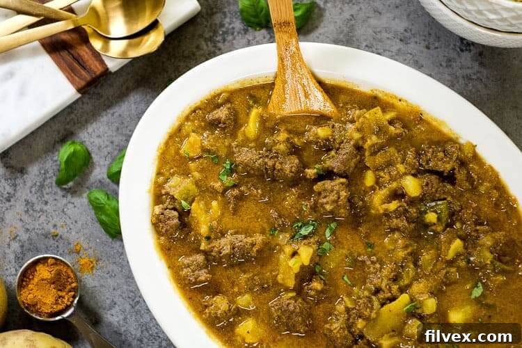A bowl of rich, hearty curry beef stew with tender beef, potatoes, and a creamy broth, garnished with fresh cilantro.