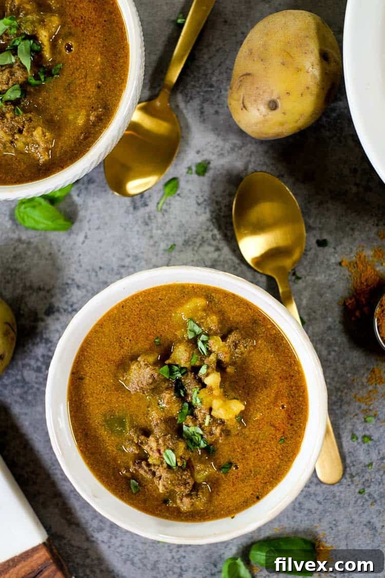A close-up view of the simmering curry beef stew inside a cooking pot, showing tender beef, potatoes, and vegetables.