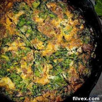 Close-up of a slice of crustless spinach quiche, showing the interior with spinach, sausage, and mushrooms