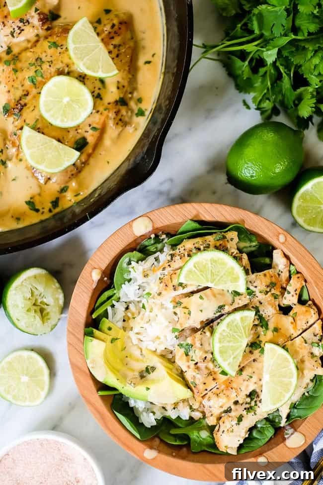 This Paleo and Whole30 friendly coconut lime chicken is so flavorful, fresh and satisfying! Coconut lime chicken in a bowl with spinach, rice, avocado and lime wedges and cilantro on top.