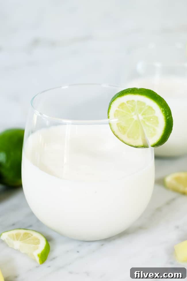 A paleo, dairy-free and refined sugar-free piña colada smoothie garnished with a slice of lime, highlighting its refreshing appeal.