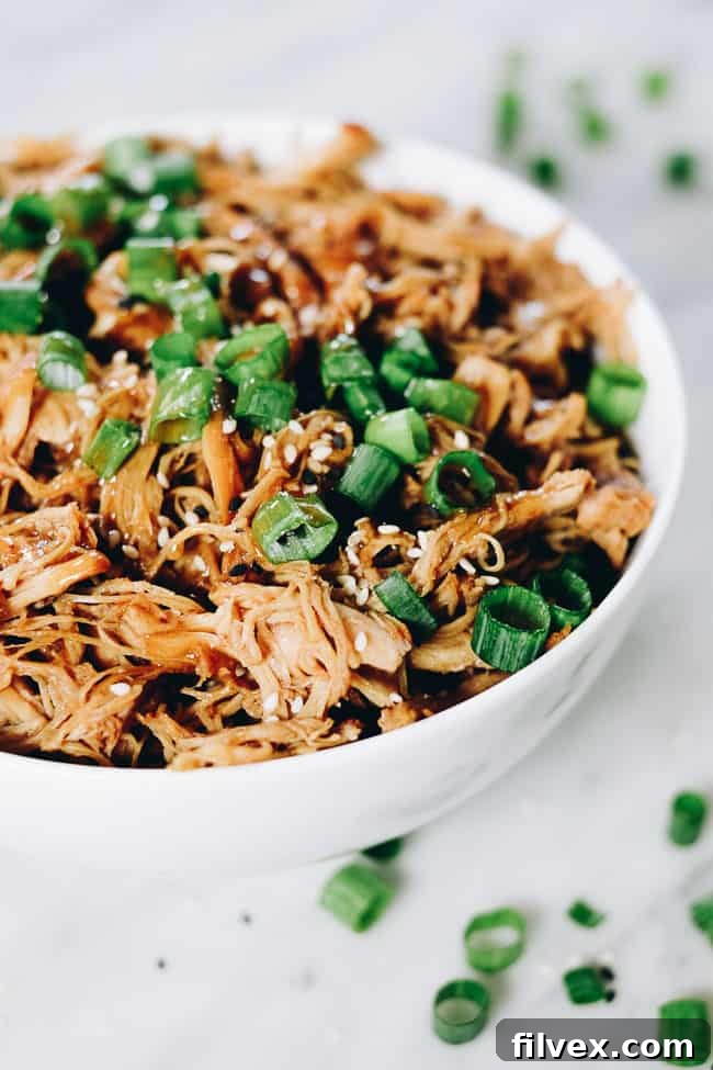 Succulent Slow Cooker Teriyaki Chicken served in a bowl, garnished with fresh green onions and sesame seeds, showcasing its rich, savory sauce.