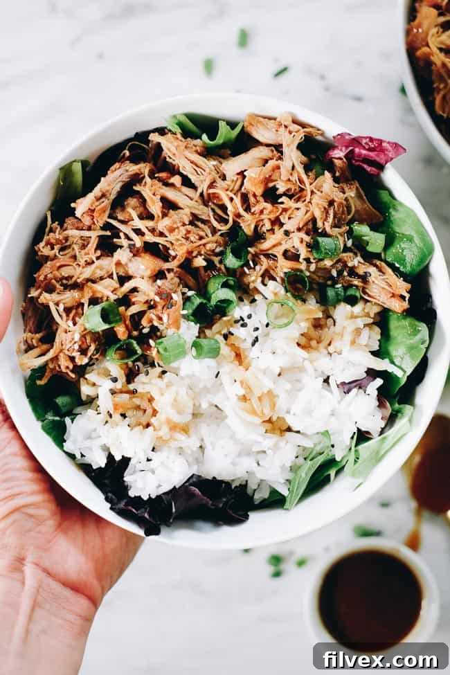 A vibrant bowl of slow cooker teriyaki chicken with white rice and fresh greens, perfectly coated in the rich teriyaki sauce.