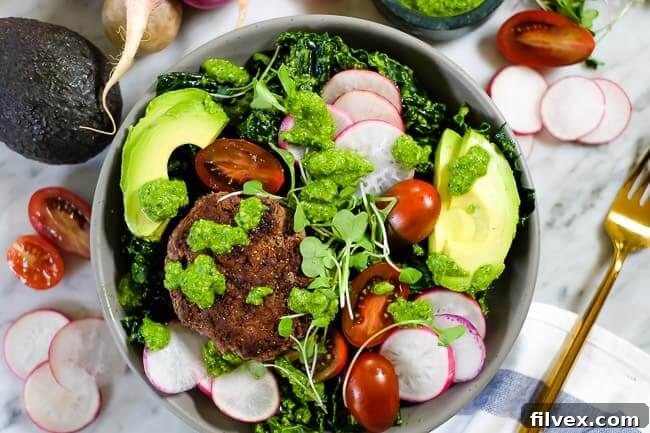 Burger salad bowl with pesto, kale, radish, tomatoes, avocado and micro greens, highlighting the vibrant colors and fresh ingredients.