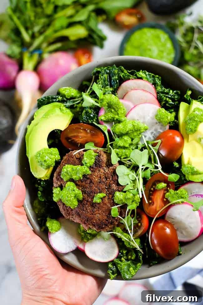 Close-up of a vibrant Pesto Burger Salad bowl with kale, radish, tomatoes, avocado, and microgreens, illustrating texture and freshness.
