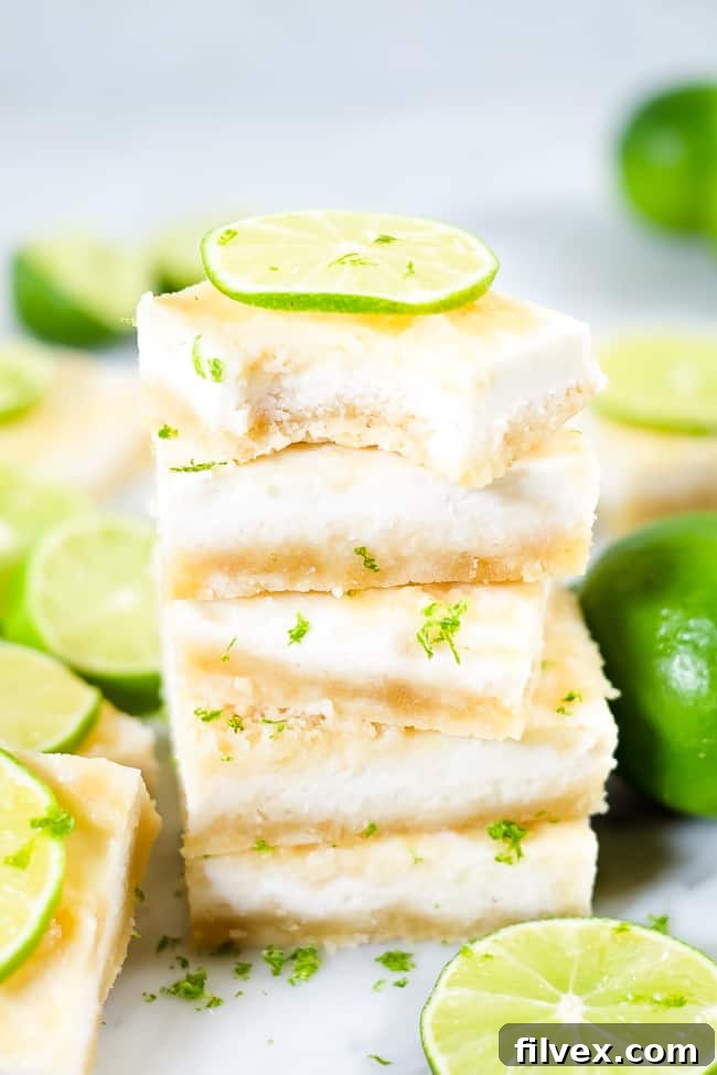 Stack of freshly made Paleo lime bars, garnished with lime zest and a slice of fresh lime.