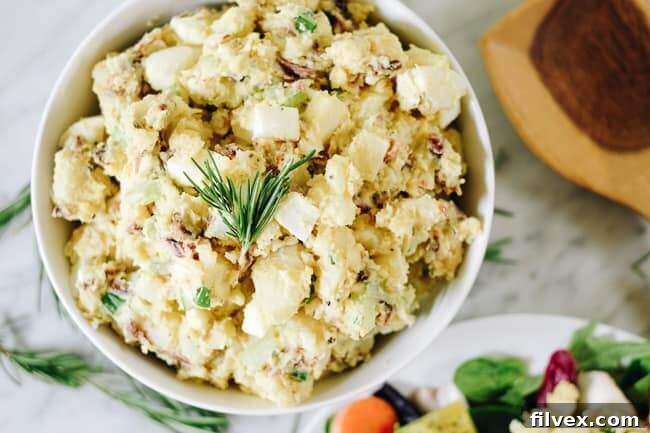 The best potato salad with bacon in a bowl with rosemary