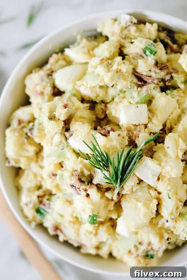 Close up shot of the best potato salad with bacon in a bowl with rosemary