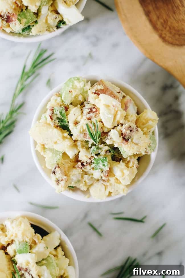 The best potato salad with bacon in a bowl with rosemary