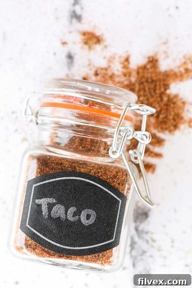 Homemade taco seasoning in a clear glass jar, resting on a rustic wooden counter, ready to be used