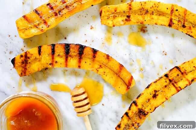 Grilled plantains drizzled with honey and sprinkled with cinnamon, arranged beautifully on a marble surface.
