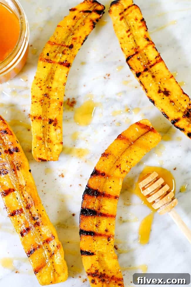 A wider shot of grilled plantains with honey and cinnamon, beautifully arranged on a marble counter top, inviting indulgence.