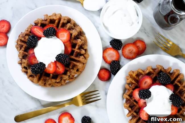 Paleo waffles topped with fresh berries and rich coconut whipped cream, ready for a healthy and delicious breakfast.