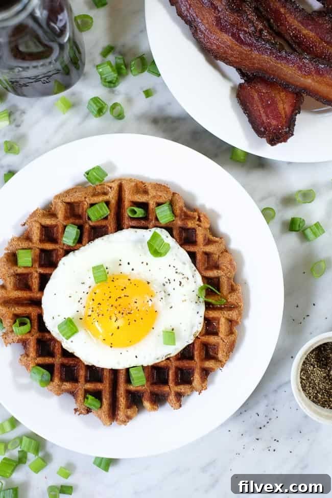 A savory Paleo waffle topped with a perfectly fried egg and freshly chopped green onion, highlighting a delicious alternative to sweet breakfast options.