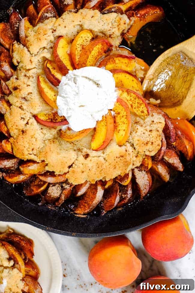 Gluten free peach cobbler with peaches and cinnamon topped with dairy-free vanilla ice cream. 