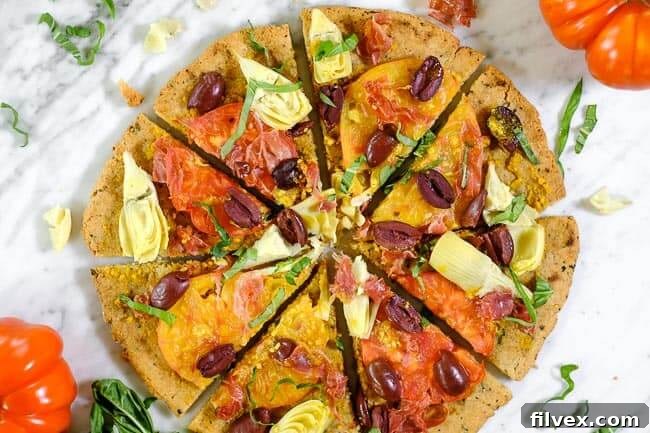 Grilled paleo pizza with heirloom tomatoes, artichoke hearts, kalamata olives, prosciutto and fresh basil, showcasing summer flavors and gluten-free, dairy-free ingredients.