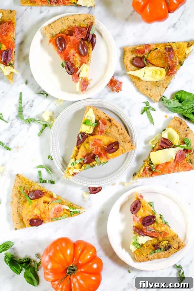 Two plates of grilled paleo pizza, featuring heirloom tomatoes, artichoke hearts, kalamata olives, prosciutto, and fresh basil, ready to be enjoyed as a gluten-free and dairy-free meal.